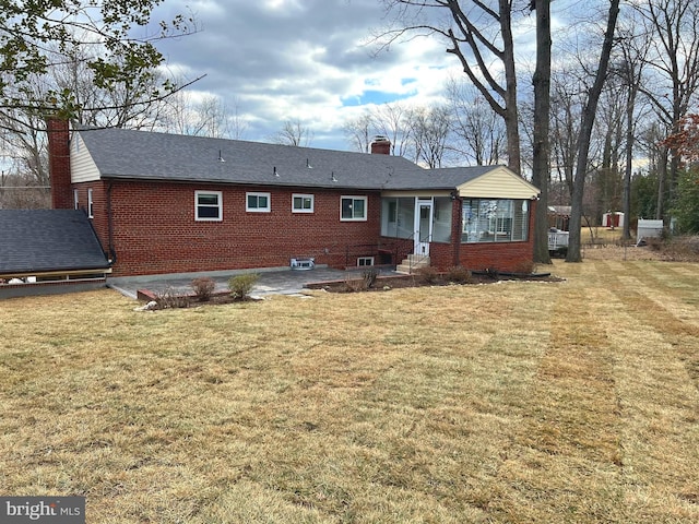 rear view of property with a yard, brick siding, a chimney, and roof with shingles