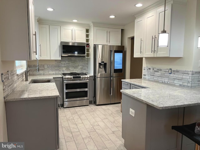 kitchen with light stone countertops, stainless steel appliances, white cabinetry, pendant lighting, and a sink