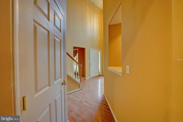 corridor featuring a towering ceiling and light hardwood / wood-style flooring