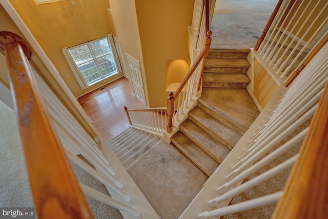 staircase featuring a high ceiling and hardwood / wood-style floors