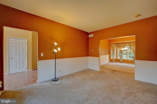 carpeted spare room featuring a chandelier