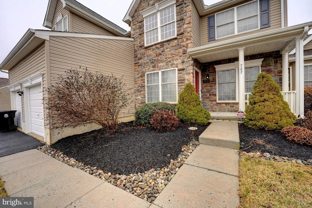 view of exterior entry featuring a garage and covered porch