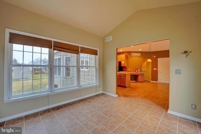 tiled empty room featuring a wealth of natural light and high vaulted ceiling