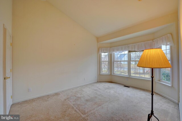 unfurnished room featuring plenty of natural light, high vaulted ceiling, and light carpet