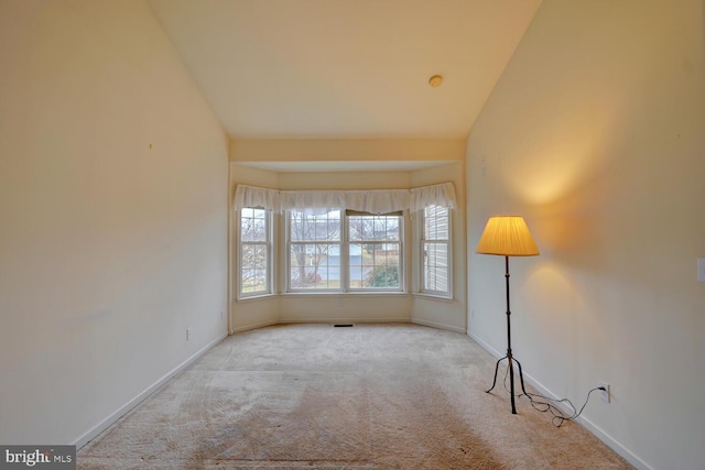 carpeted spare room featuring lofted ceiling