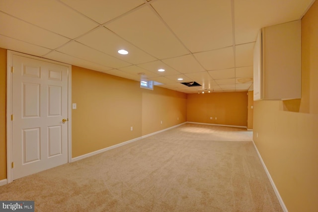 basement with light carpet and a paneled ceiling