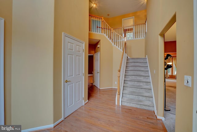 staircase featuring a towering ceiling and wood-type flooring