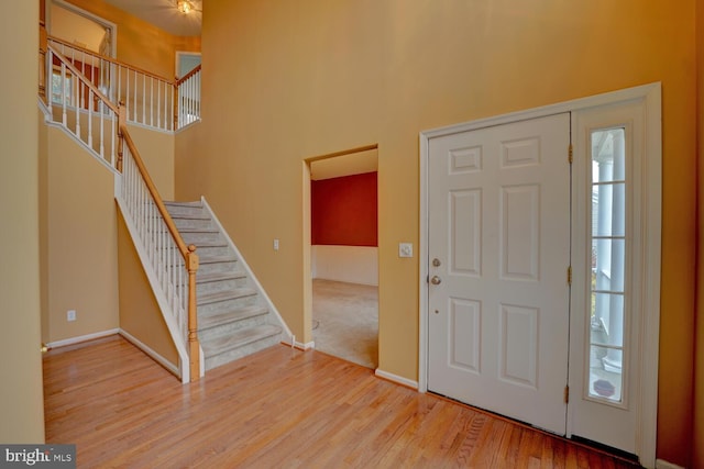 entrance foyer with wood-type flooring and a towering ceiling