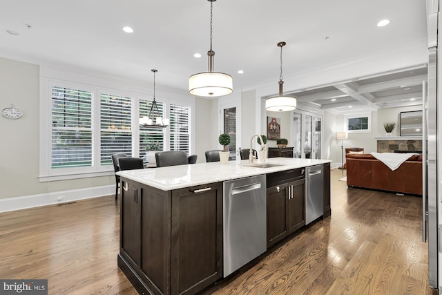 kitchen featuring decorative light fixtures, dishwasher, sink, a kitchen island with sink, and dark brown cabinets