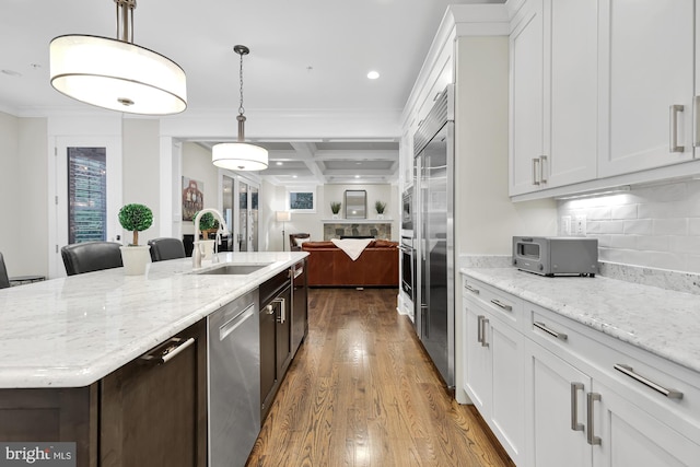 kitchen featuring a kitchen island with sink, sink, and white cabinets