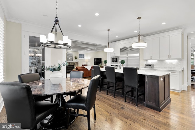 dining room with beam ceiling, ornamental molding, coffered ceiling, and light hardwood / wood-style floors