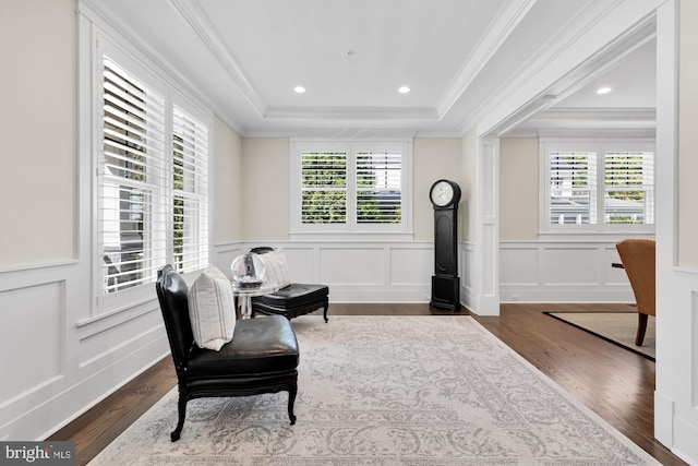 living area featuring a raised ceiling, crown molding, and dark wood-type flooring