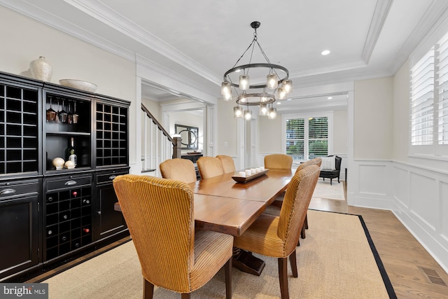 dining area featuring crown molding, a chandelier, and light wood-type flooring