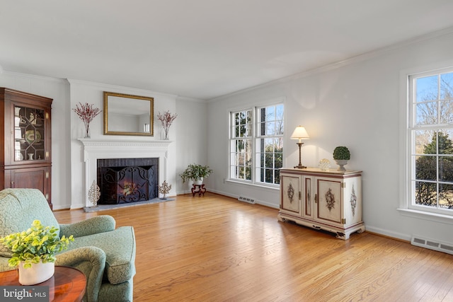 living room with ornamental molding, a wealth of natural light, and light wood-type flooring