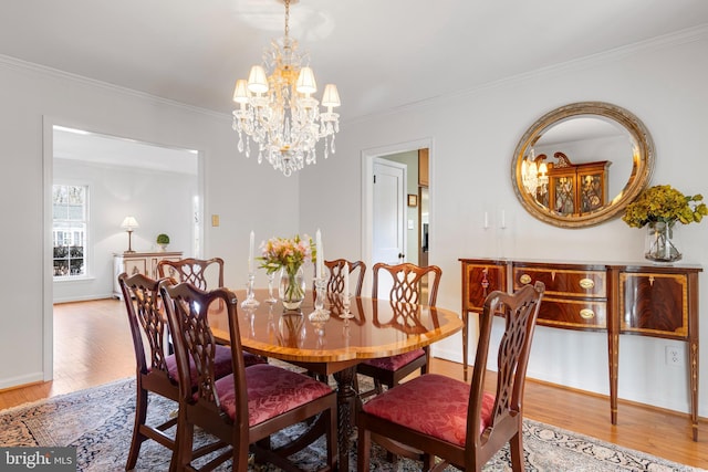 dining room with hardwood / wood-style flooring, crown molding, and an inviting chandelier