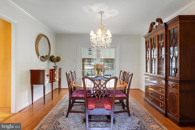 dining area with crown molding, hardwood / wood-style floors, and an inviting chandelier