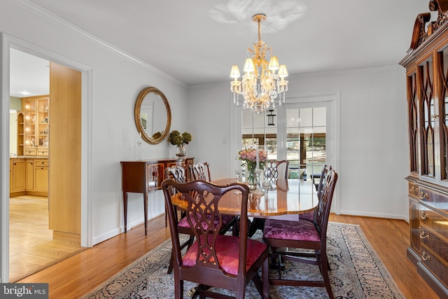 dining area with crown molding, a notable chandelier, and light hardwood / wood-style flooring