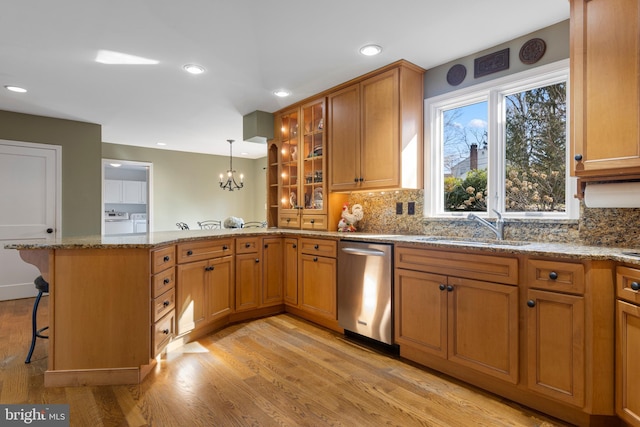 kitchen featuring washer and dryer, a breakfast bar, sink, stainless steel dishwasher, and kitchen peninsula