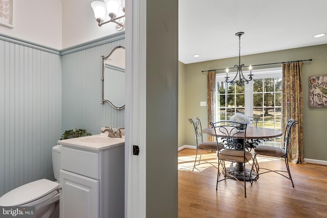 bathroom with wood-type flooring, toilet, a chandelier, and vanity