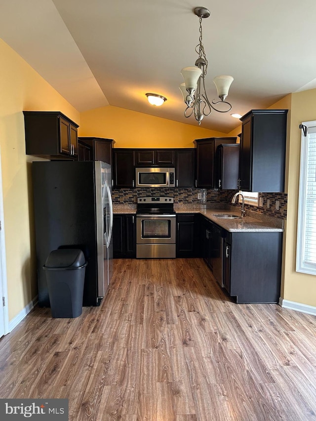 kitchen with vaulted ceiling, decorative light fixtures, tasteful backsplash, sink, and stainless steel appliances