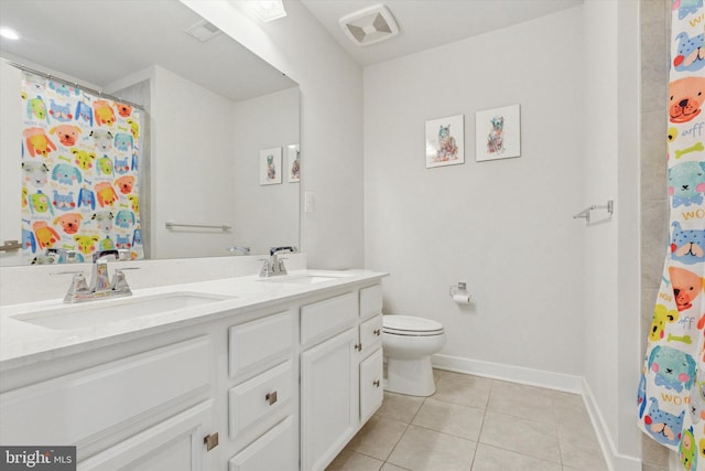 bathroom featuring tile patterned flooring, double vanity, toilet, and a sink