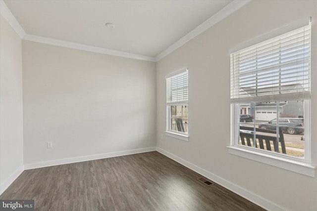 empty room with visible vents, baseboards, wood finished floors, and crown molding