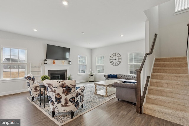 living room featuring a wealth of natural light, dark wood-type flooring, and stairs