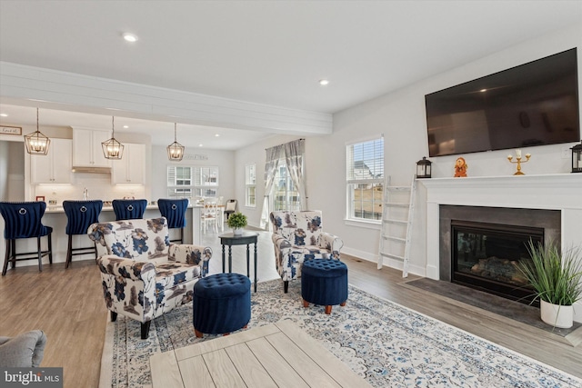 living room with a fireplace with flush hearth, plenty of natural light, recessed lighting, and light wood finished floors