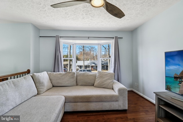 living room with ceiling fan, a textured ceiling, baseboards, and wood finished floors