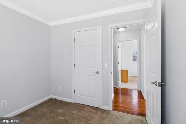 unfurnished bedroom with carpet flooring, crown molding, and baseboards