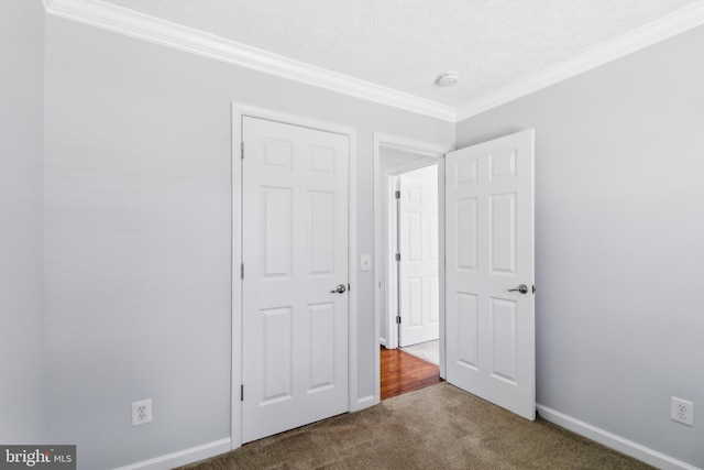 unfurnished bedroom featuring carpet floors, baseboards, and crown molding