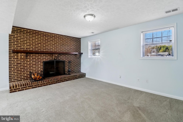 unfurnished living room featuring carpet floors, visible vents, a brick fireplace, a textured ceiling, and baseboards