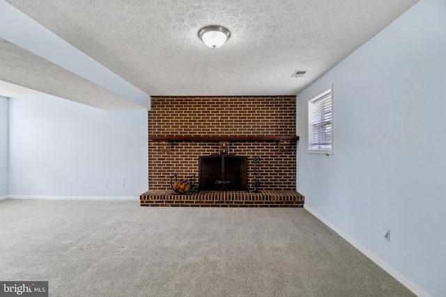 unfurnished living room with a textured ceiling, carpet floors, a fireplace, visible vents, and baseboards