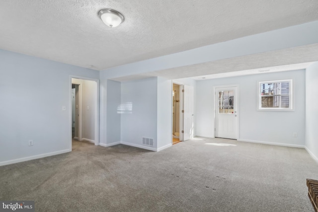 carpeted spare room featuring a textured ceiling, visible vents, and baseboards