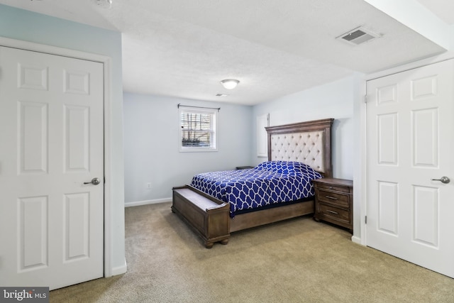 bedroom with baseboards, visible vents, a textured ceiling, and light colored carpet