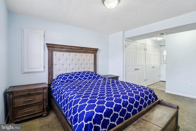 bedroom featuring a textured ceiling, visible vents, baseboards, a closet, and carpet