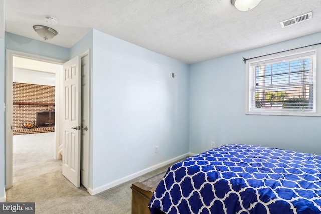 bedroom with baseboards, visible vents, carpet, a textured ceiling, and a fireplace