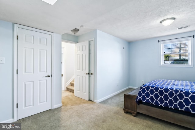 bedroom featuring visible vents, carpet flooring, a textured ceiling, and baseboards