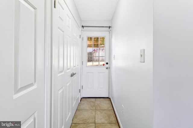 doorway with light tile patterned floors and baseboards