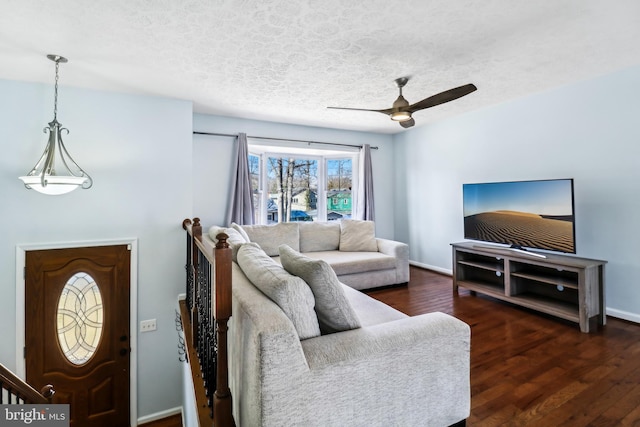 living area with ceiling fan, a textured ceiling, baseboards, and wood finished floors