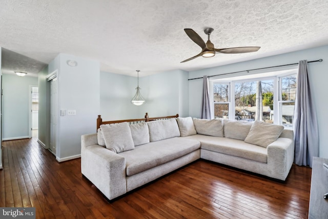 living room with dark wood-style floors, ceiling fan, a textured ceiling, and baseboards