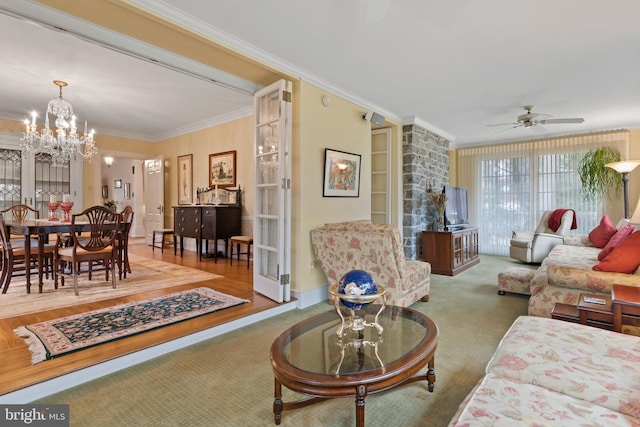 living room with crown molding, carpet, and ceiling fan with notable chandelier