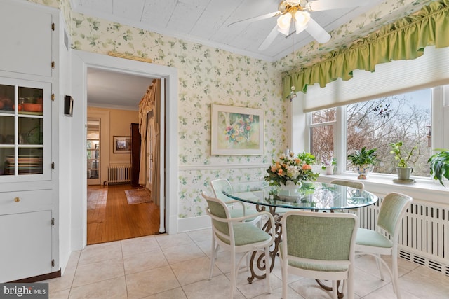 tiled dining area featuring ornamental molding, radiator, and ceiling fan