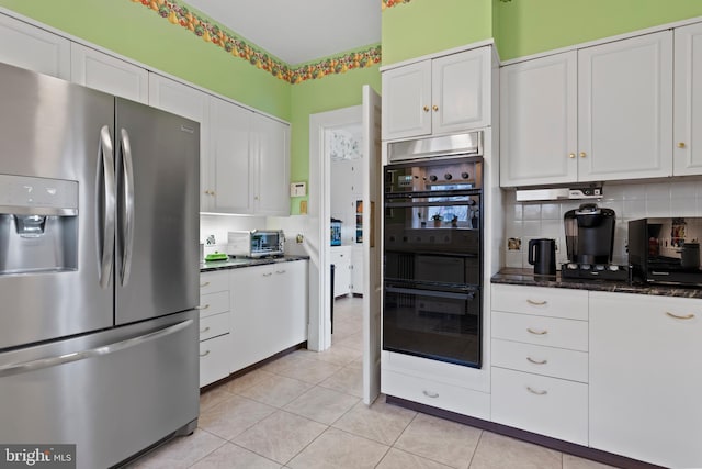 kitchen with white cabinetry, dark stone counters, stainless steel fridge, and decorative backsplash