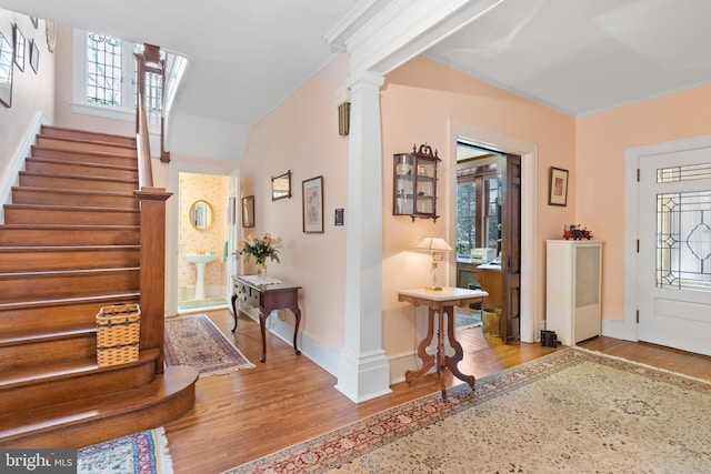 entrance foyer with ornate columns, crown molding, and light hardwood / wood-style flooring