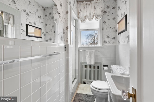 bathroom featuring tile walls, sink, radiator heating unit, and toilet