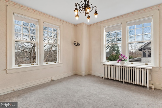 carpeted spare room featuring radiator and a notable chandelier