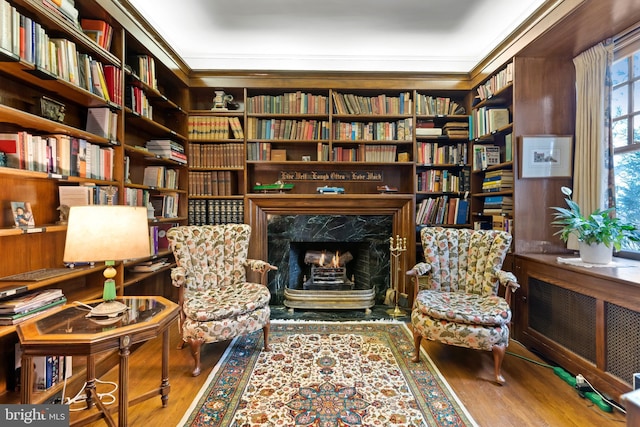 living area featuring radiator heating unit, ornamental molding, hardwood / wood-style floors, and a high end fireplace