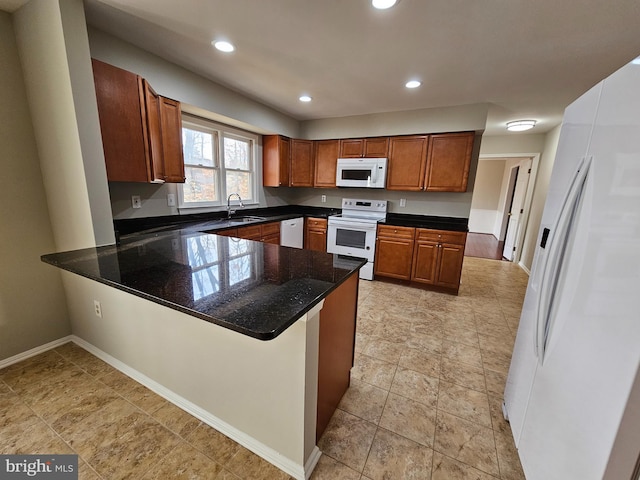 kitchen featuring white appliances, a kitchen breakfast bar, kitchen peninsula, and dark stone countertops