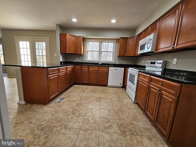 kitchen with white appliances, plenty of natural light, kitchen peninsula, and sink